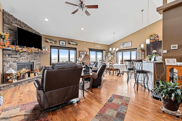 living room with a fireplace, ceiling fan with notable chandelier, light hardwood / wood-style floors, and high vaulted ceiling