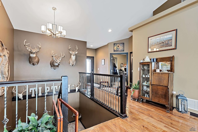 hallway featuring hardwood / wood-style flooring and an inviting chandelier