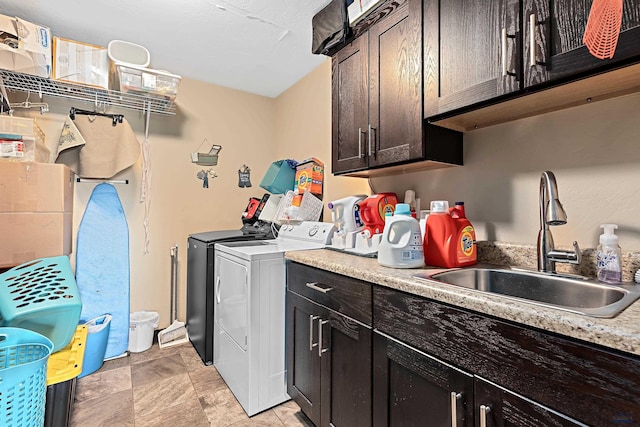 laundry area featuring washing machine and clothes dryer, cabinets, and sink