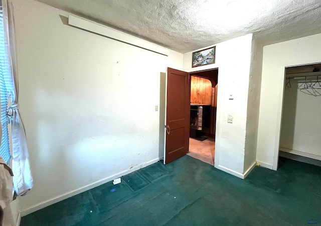 unfurnished bedroom with dark colored carpet, a textured ceiling, and a closet