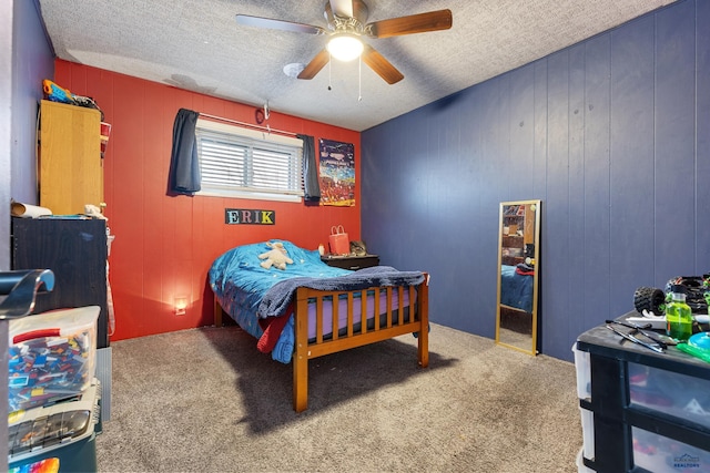 bedroom with carpet flooring, a textured ceiling, ceiling fan, and wood walls