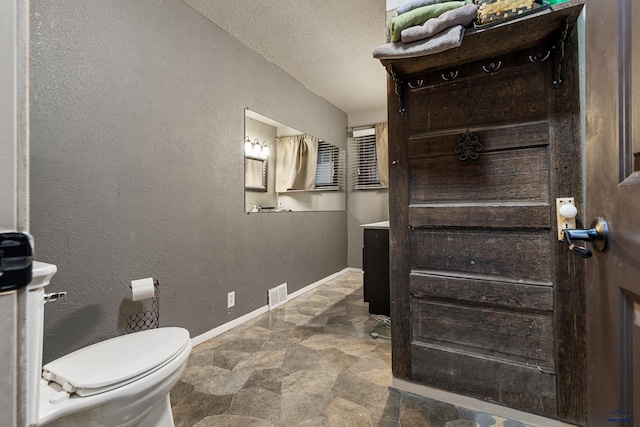 bathroom featuring vanity, toilet, and a textured ceiling