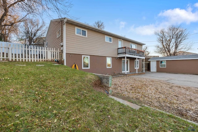 back of property featuring an outbuilding, a yard, a balcony, and a garage