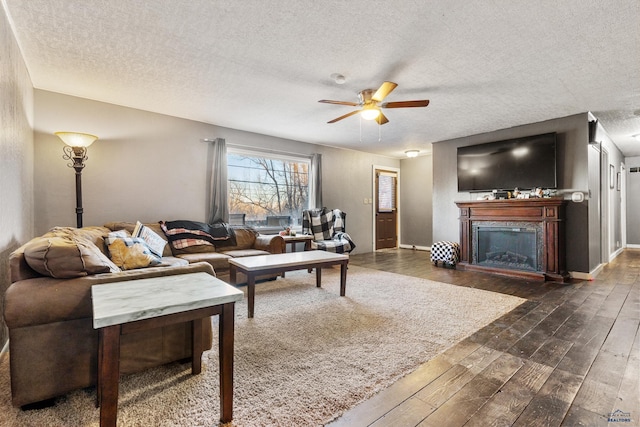 living room with ceiling fan, dark wood-type flooring, and a textured ceiling