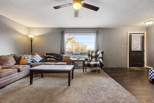 living room featuring ceiling fan, dark hardwood / wood-style flooring, and a textured ceiling