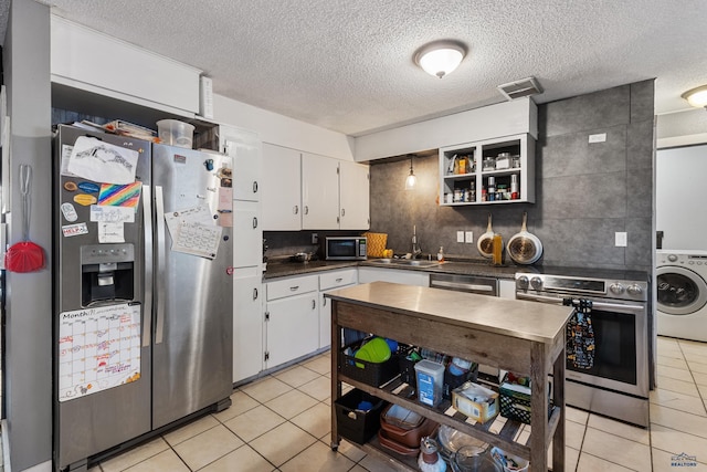 kitchen featuring washer / clothes dryer, white cabinets, a textured ceiling, and appliances with stainless steel finishes