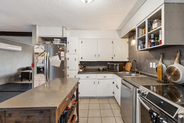 kitchen featuring white cabinetry, sink, stainless steel appliances, a wall mounted air conditioner, and a textured ceiling