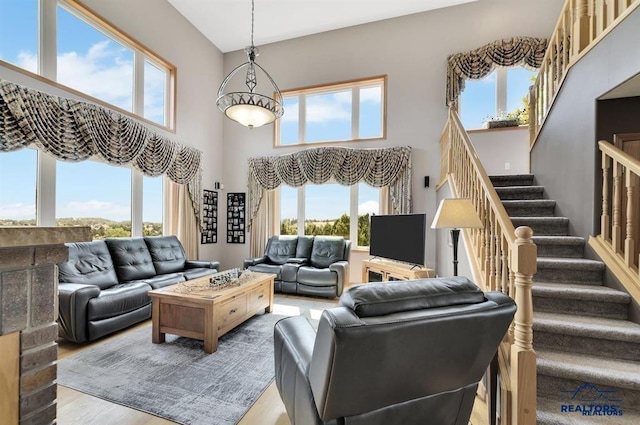 living room featuring plenty of natural light, a towering ceiling, and light hardwood / wood-style floors