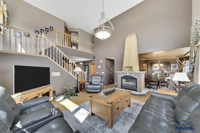 living room featuring hardwood / wood-style floors, a fireplace, a high ceiling, and an inviting chandelier