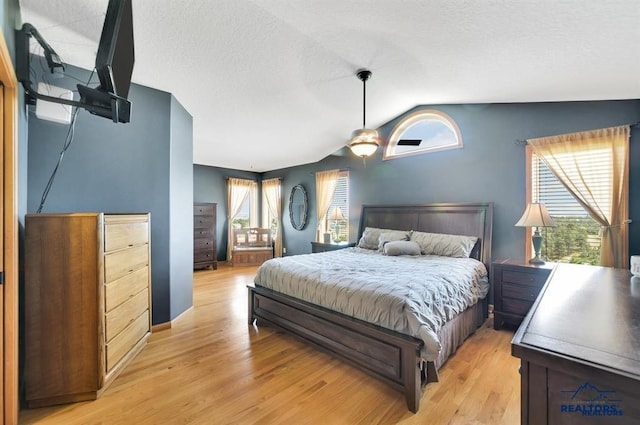 bedroom featuring multiple windows, ceiling fan, vaulted ceiling, and light wood-type flooring