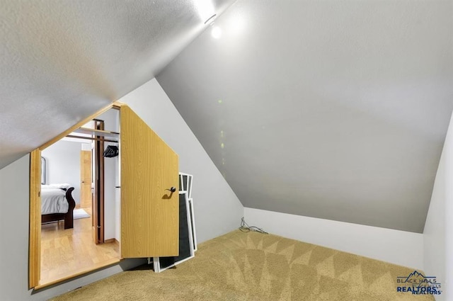 bonus room featuring a textured ceiling, carpet, and vaulted ceiling