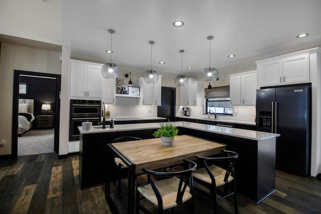 kitchen with pendant lighting, dark wood-type flooring, a center island, and black appliances