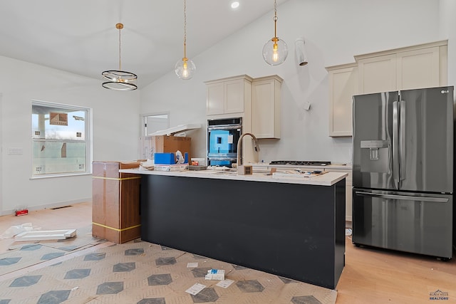 kitchen featuring stainless steel refrigerator with ice dispenser, an island with sink, pendant lighting, cream cabinetry, and light wood-type flooring