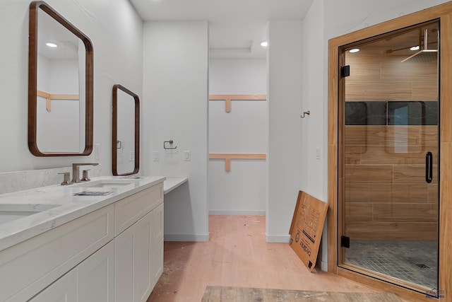 bathroom with a shower with shower door, ceiling fan, wood-type flooring, and vanity