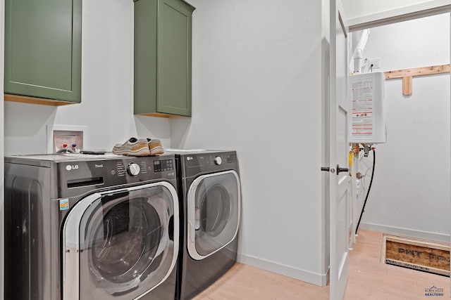 clothes washing area featuring cabinets, light wood-type flooring, and washing machine and clothes dryer