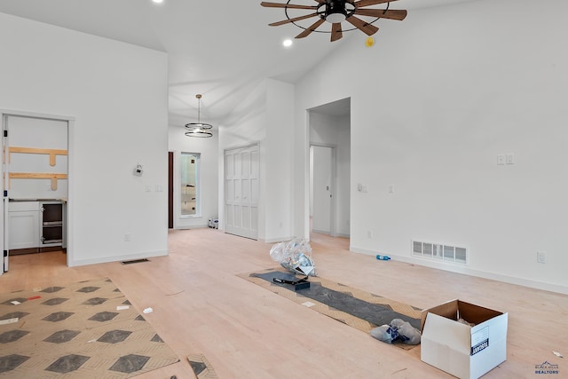 living room featuring ceiling fan, high vaulted ceiling, and light hardwood / wood-style flooring