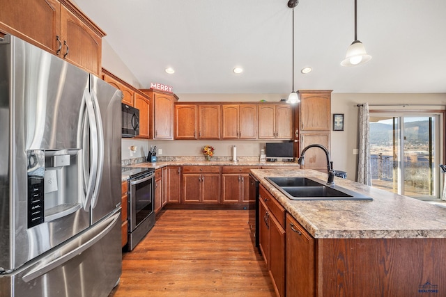 kitchen with sink, wood-type flooring, decorative light fixtures, a center island with sink, and black appliances