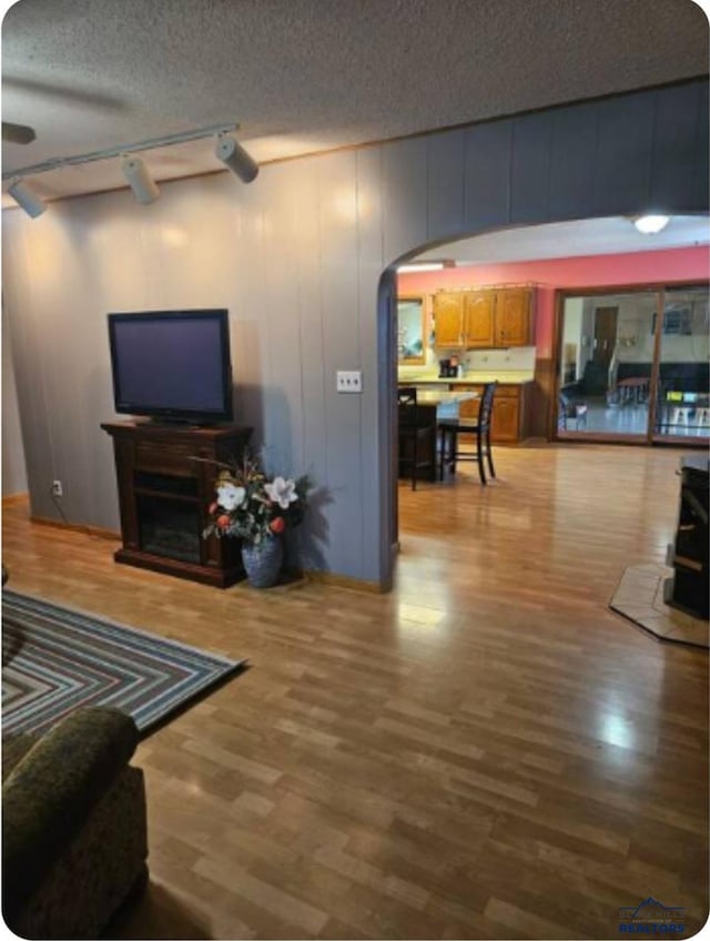 living room with rail lighting, light hardwood / wood-style floors, and a textured ceiling
