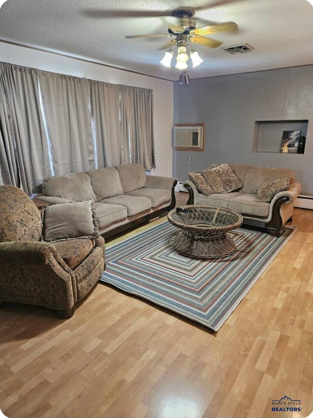 living room with hardwood / wood-style floors, ceiling fan, baseboard heating, a textured ceiling, and a wall mounted AC