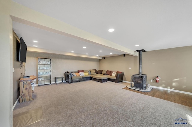 unfurnished living room featuring beam ceiling, a wood stove, and light wood-type flooring