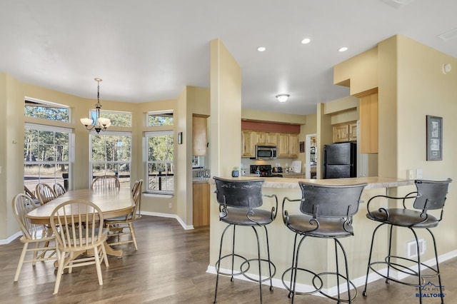 kitchen with kitchen peninsula, black appliances, decorative light fixtures, an inviting chandelier, and dark hardwood / wood-style floors