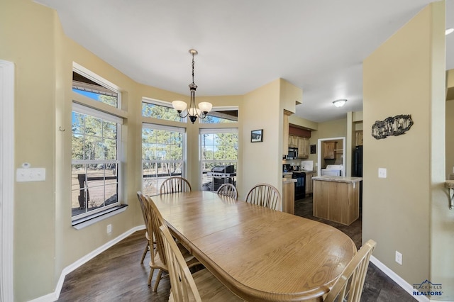 dining area featuring washer / dryer, dark wood-type flooring, a healthy amount of sunlight, and a notable chandelier