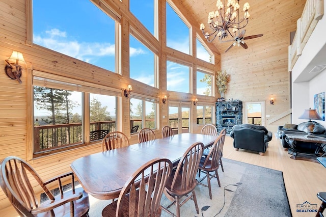 dining room featuring a wealth of natural light, light hardwood / wood-style floors, ceiling fan with notable chandelier, and high vaulted ceiling