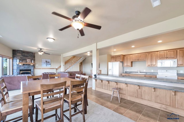 tiled dining room featuring ceiling fan, a fireplace, and sink