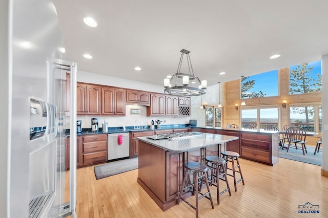 kitchen with a notable chandelier, stainless steel appliances, decorative light fixtures, and light hardwood / wood-style floors