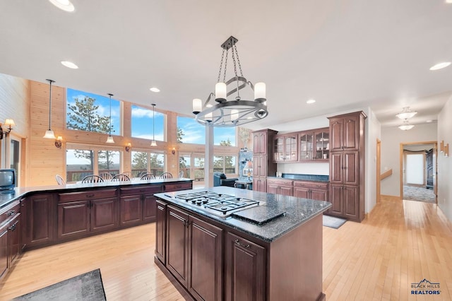 kitchen with dark brown cabinetry, hanging light fixtures, and light hardwood / wood-style floors