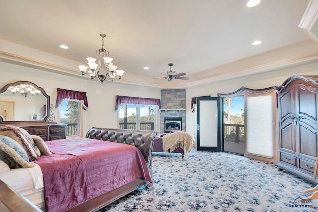 bedroom featuring access to outside, ceiling fan with notable chandelier, carpet flooring, a tray ceiling, and a large fireplace