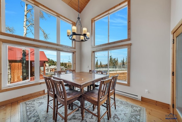 dining space with a chandelier, a baseboard radiator, high vaulted ceiling, and light hardwood / wood-style flooring