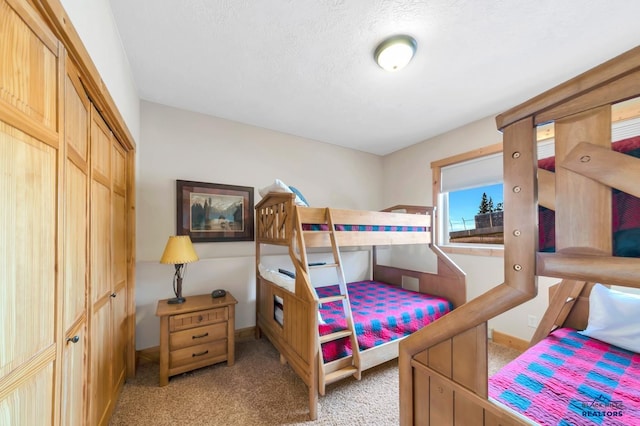 bedroom featuring light carpet, a textured ceiling, and a closet