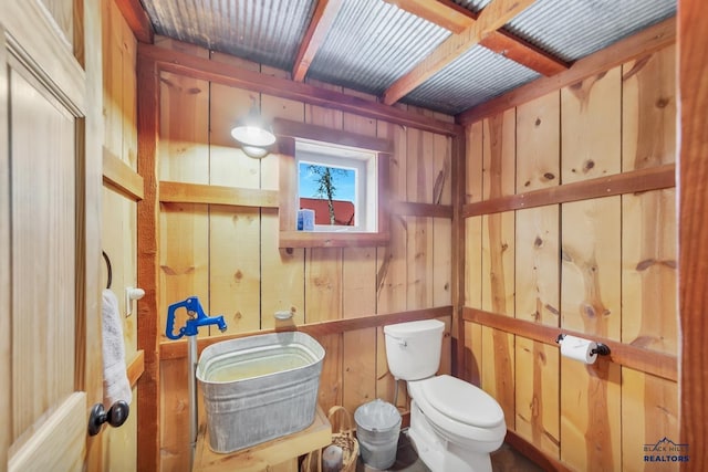 bathroom with toilet and wooden walls