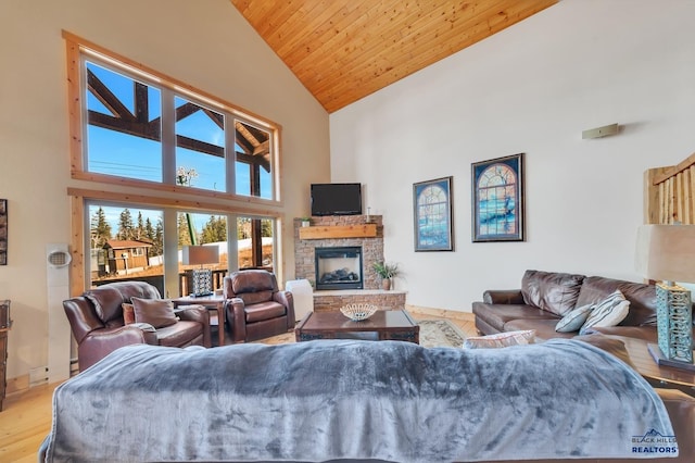 living room with a stone fireplace, light hardwood / wood-style flooring, high vaulted ceiling, and wooden ceiling