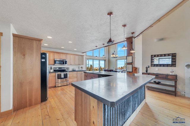 kitchen with light brown cabinets, stainless steel appliances, light hardwood / wood-style floors, a textured ceiling, and decorative light fixtures