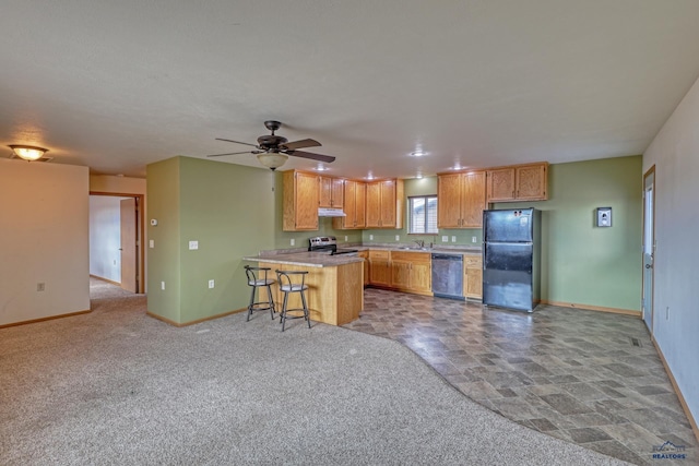 kitchen with light carpet, ceiling fan, appliances with stainless steel finishes, kitchen peninsula, and a breakfast bar area