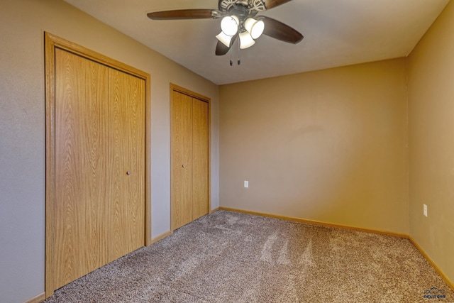 unfurnished bedroom featuring ceiling fan, carpet, and two closets