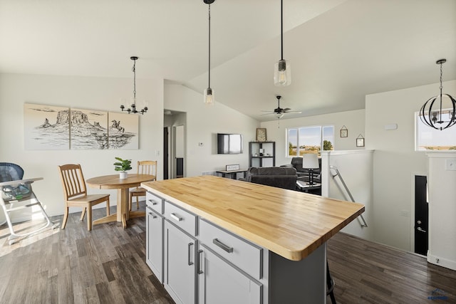 kitchen featuring dark wood-type flooring, pendant lighting, lofted ceiling, a center island, and butcher block counters