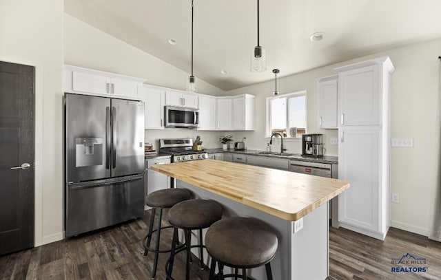 kitchen with wood counters, white cabinets, hanging light fixtures, and appliances with stainless steel finishes