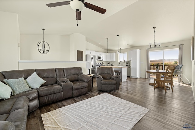 living room featuring ceiling fan with notable chandelier, dark hardwood / wood-style flooring, sink, and vaulted ceiling