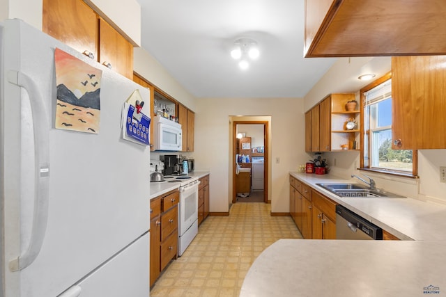 kitchen with washer / dryer, white appliances, and sink