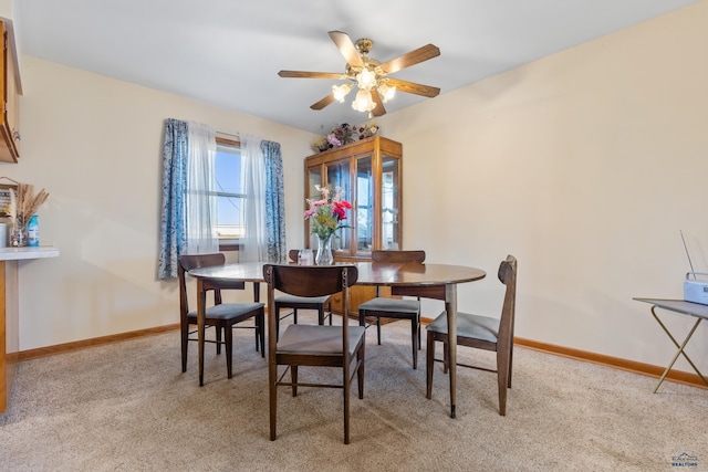 carpeted dining area with ceiling fan