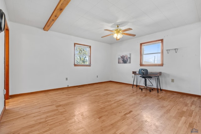 spare room featuring beamed ceiling, light wood-type flooring, and ceiling fan