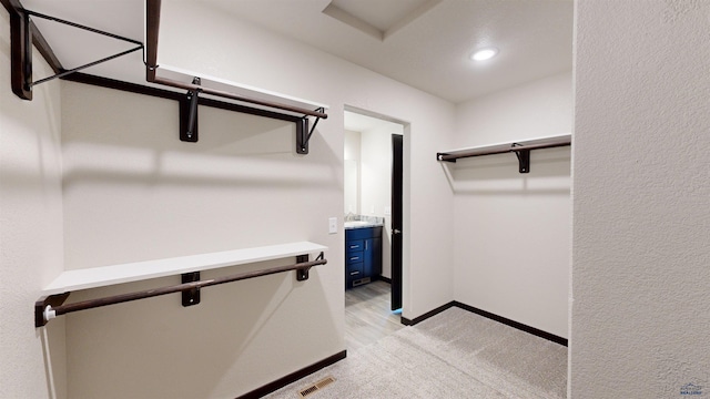 walk in closet featuring light colored carpet