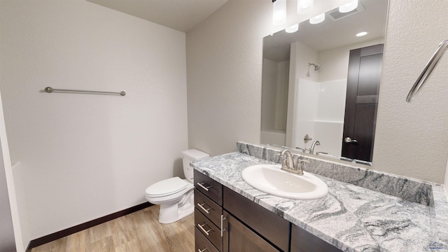 bathroom featuring hardwood / wood-style flooring, vanity, a shower, and toilet