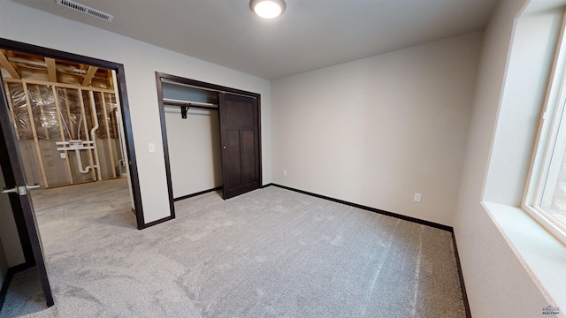 unfurnished bedroom featuring light colored carpet and a closet