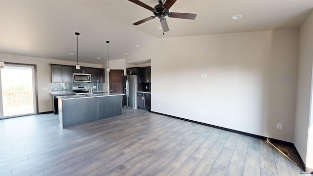 kitchen with sink, dark hardwood / wood-style floors, pendant lighting, stainless steel appliances, and a kitchen island with sink