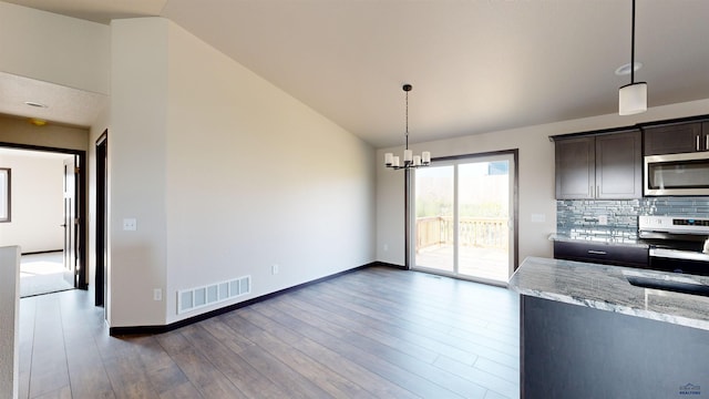 kitchen featuring stainless steel appliances, vaulted ceiling, hanging light fixtures, and dark brown cabinets