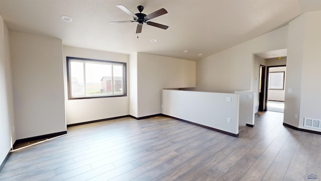 unfurnished room featuring ceiling fan, light wood-type flooring, and vaulted ceiling